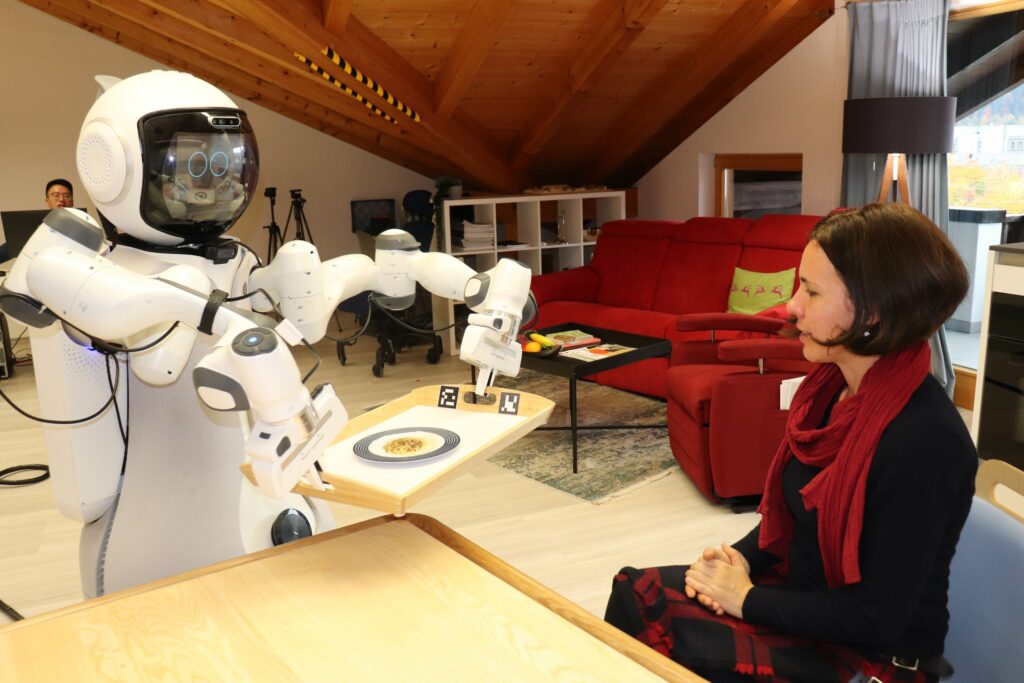 Der Assistenz-Roboter GARMI bringt Eva Theresa Jahn ein Tablett mit Essen.